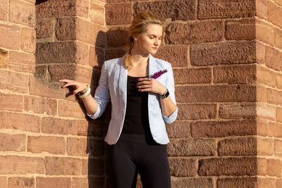 Full length of young woman standing against wall