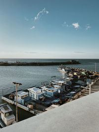 Boats moored at harbor against sky