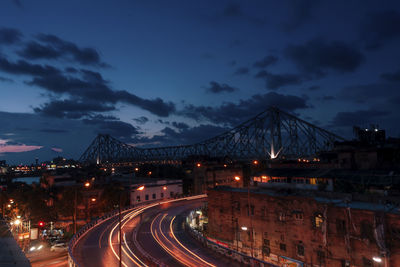 Light trails on road in city against sky at night