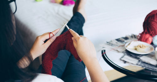 Woman knitting wool while sitting at home