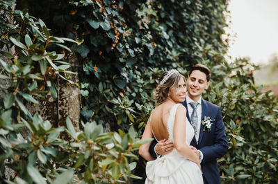 Young couple standing against plants