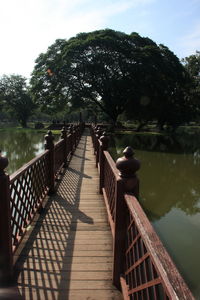 Boardwalk by footbridge against sky