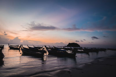 Boats moored in sea against sky during sunset