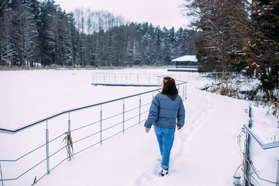 Rear view of man walking on snow covered field