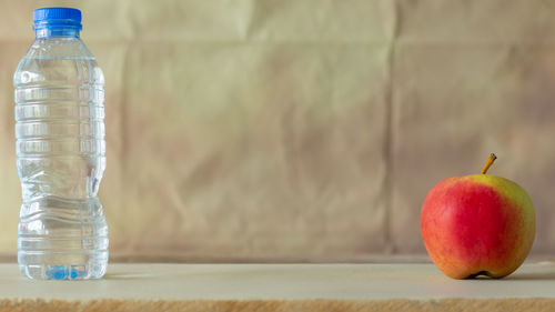 Close-up of apples in glass on table against wall