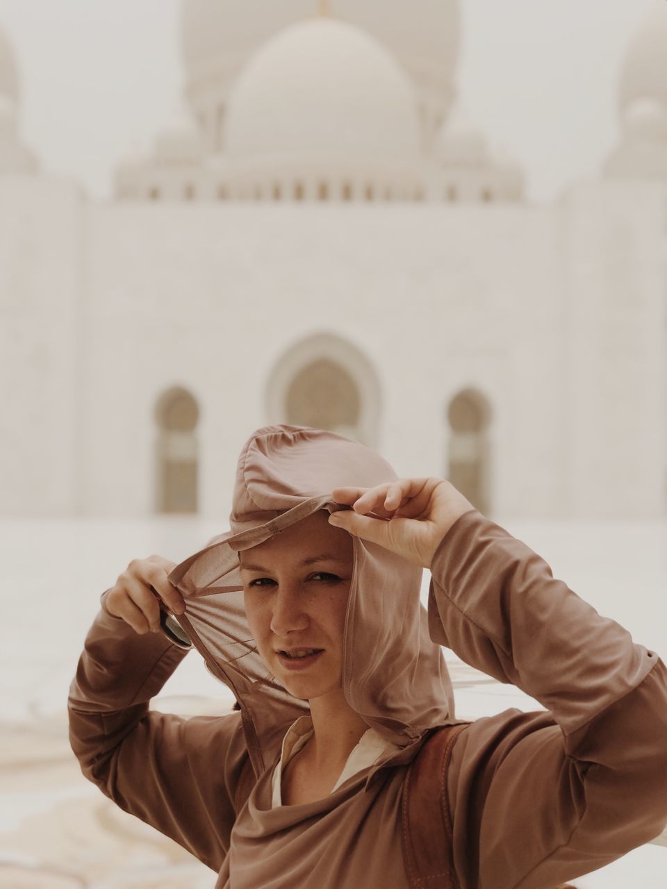 one person, portrait, headshot, clothing, lifestyles, focus on foreground, front view, architecture, real people, hat, young women, built structure, casual clothing, leisure activity, smiling, young adult, day, women, hairstyle