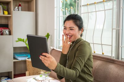 Woman using tablet while sitting on sofa