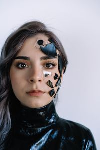 Portrait of beautiful young woman with shattered broken glass on face against white background