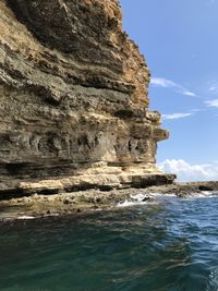 Rock formation in sea against sky