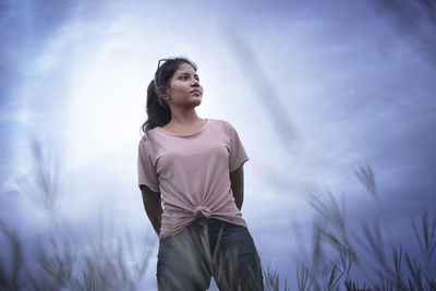 Portrait of young woman standing against trees