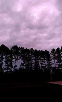 Low angle view of silhouette trees against cloudy sky