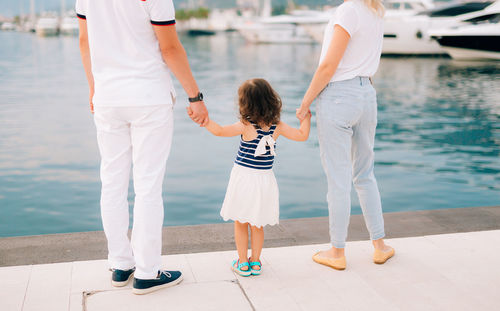 Rear view of mother with daughter standing in water