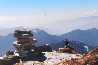 Bird sitting on stack of rocks on mountain against sky