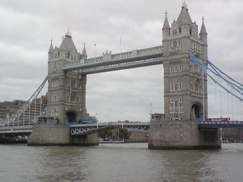 Low angle view of tower bridge over thames river against cloudy sky in city