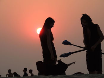 Silhouette man and woman against sky during sunset