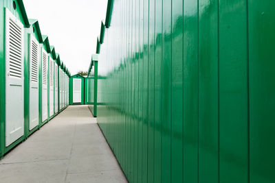 View down a row of green painted wooden beach cabins with white doors