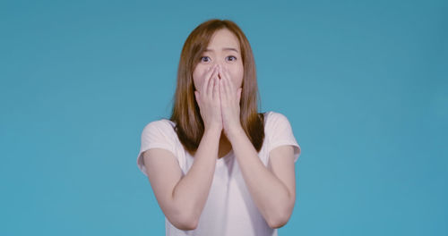 Portrait of young woman against blue background