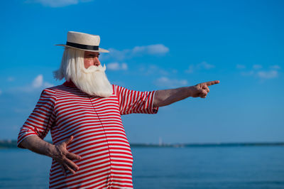 Midsection of person standing by sea against sky