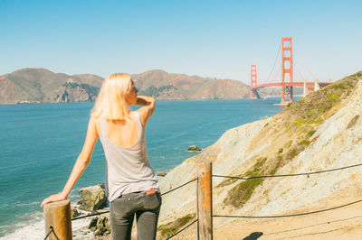 Rear view of woman looking at golden gate bridge against sky