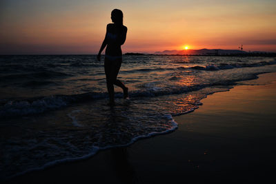 Silhouette man on beach against sky during sunset