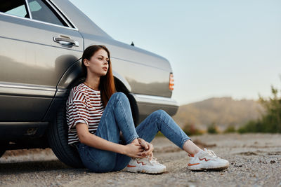 Low angle view of woman sitting on car