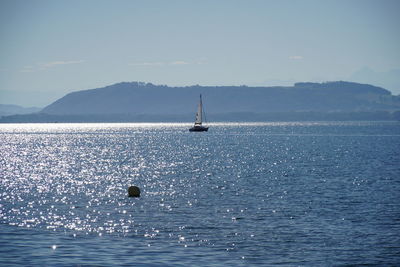 Sailboat sailing on sea against sky