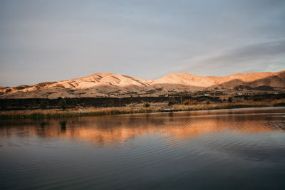 Scenic view of lake by mountains against sky