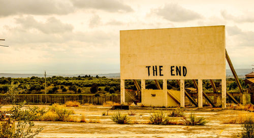 Information sign on field by sea against sky