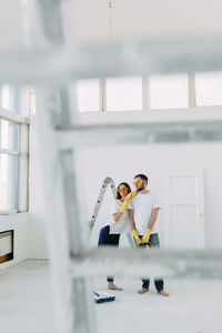 Happy smiling married couple engaged in renovation repair in the room of the house preparing to move