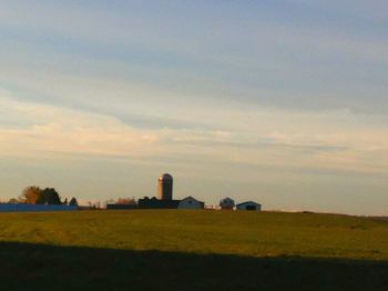 Scenic view of grassy field against sky at sunset