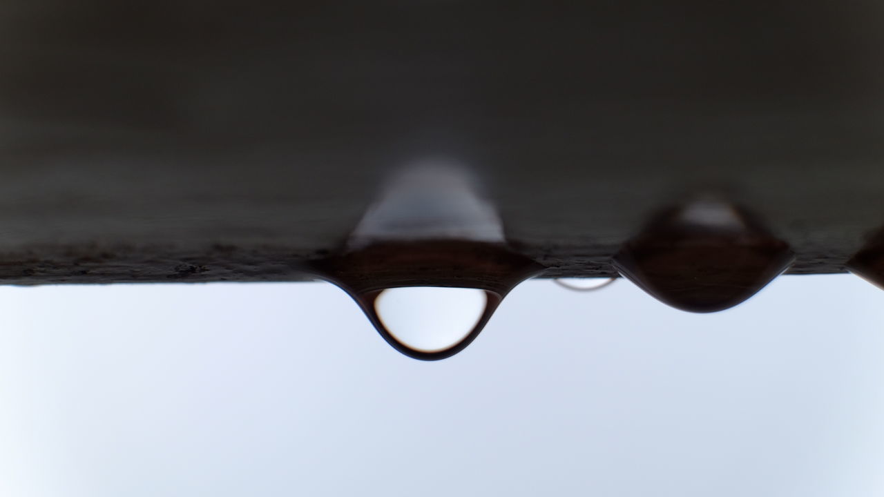 CLOSE-UP OF WATER DROP AGAINST SKY IN SUNLIGHT