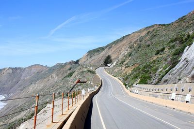 Empty road leading towards mountains against sky