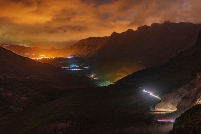 Panoramic view of illuminated mountains against sky at sunset