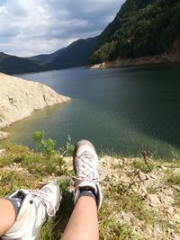 Low section of person in sea by mountains