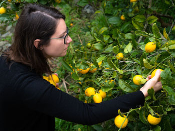 Young woman with fruits growing on plant