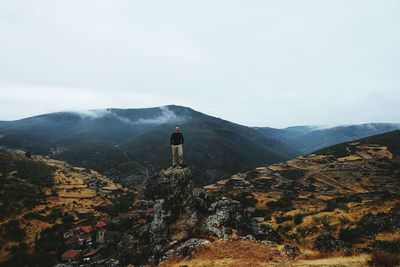 Man standing on rock in mountain range against sky