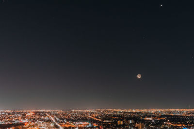 Illuminated cityscape against sky at night