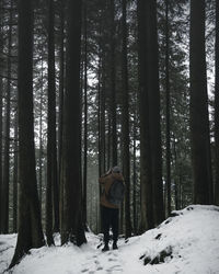 Rear view of man standing in snow covered forest