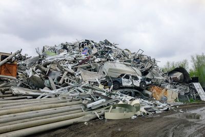 Heap of garbage at junkyard against cloudy sky