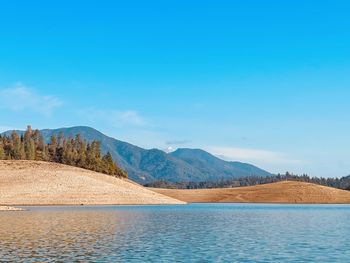 Scenic view of lake and mountains against blue sky