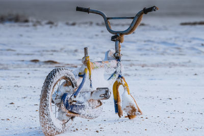 Abandoned broken bicycle on snow covered beach