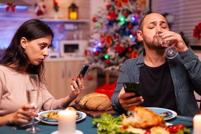 Young man and woman having food on christmas tree