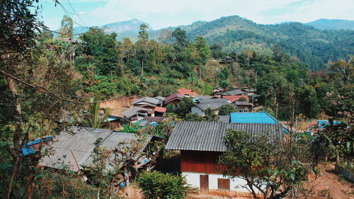 Houses and trees in village against sky