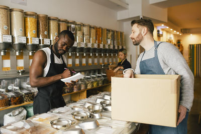 Multiracial male colleagues working in food store