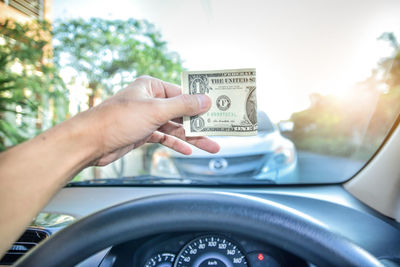 Cropped hand of man holding paper currency in car