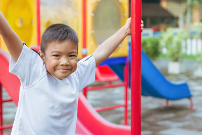Portrait of happy boy on slide at playground