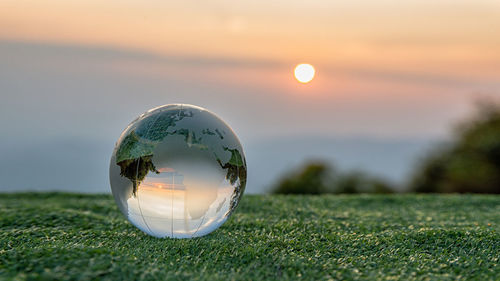 Close-up of crystal ball on grass at sunset