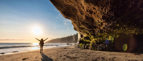 Man standing at beach against sky during sunset