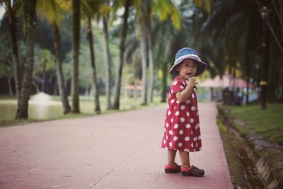 Full length of cute girl wearing hat against trees