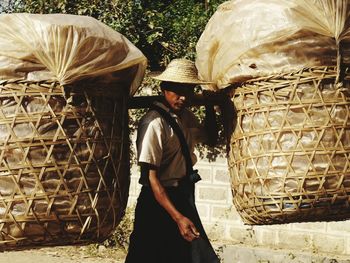 Man carrying large wicker baskets on shoulder